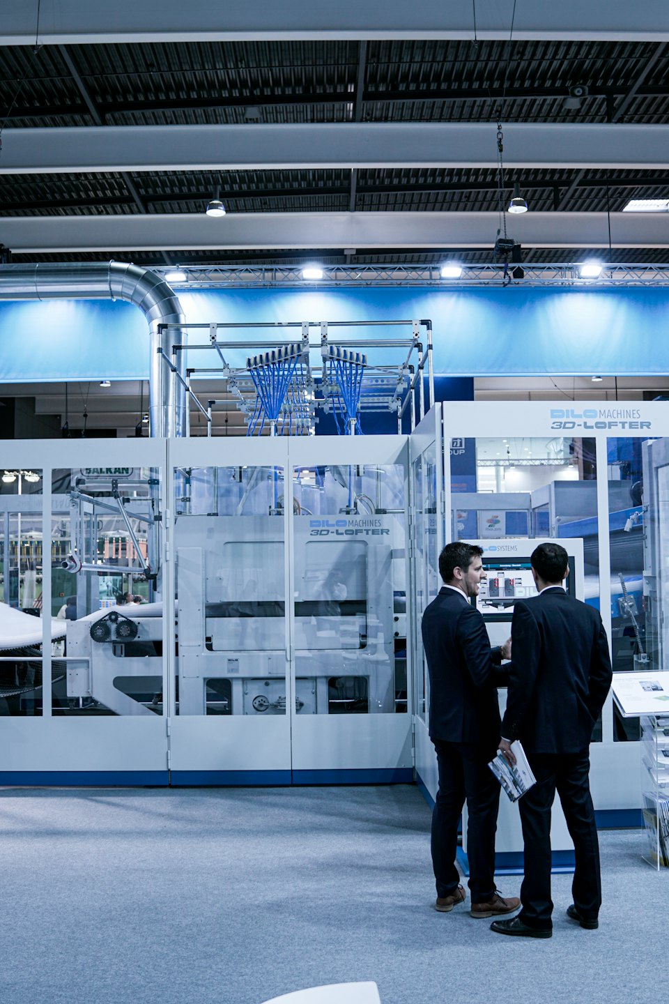 Two businessmen discuss a large industrial machine with blue tubes.